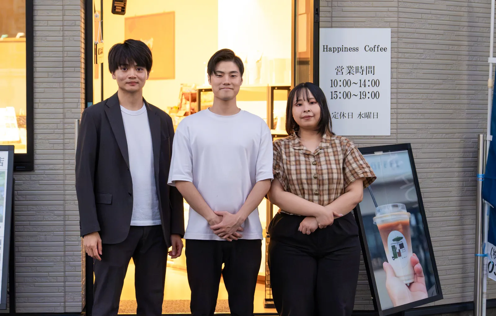 コーヒー店の前に並ぶ3人のスタッフ